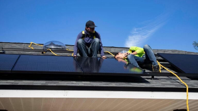 solar installer on roof with panels, safety harness visible
