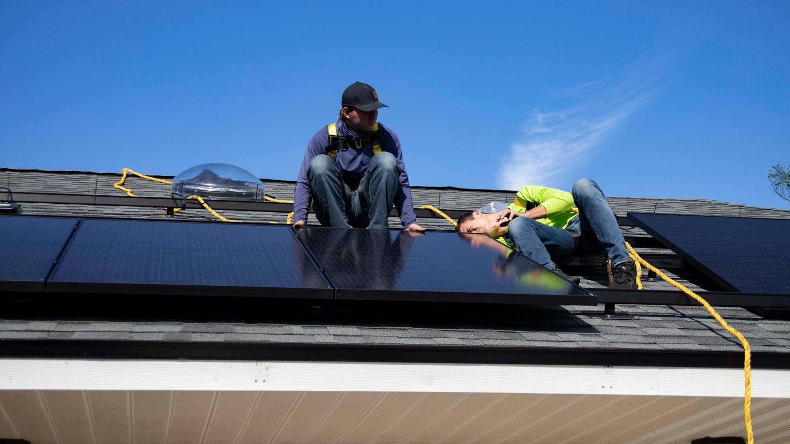 solar installer on roof with panels, safety harness visible